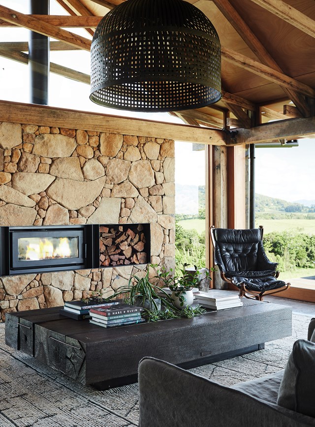[This barn-style home](https://www.homestolove.com.au/barn-home-byron-bay-hinterland-22459|target="_blank") is the perfect setting for a generous wood-burning fireplace. The rustic nature of the build lends itself to making a feature of the woodpile, which hovers above a massive dark-stained salvaged timber coffee table.