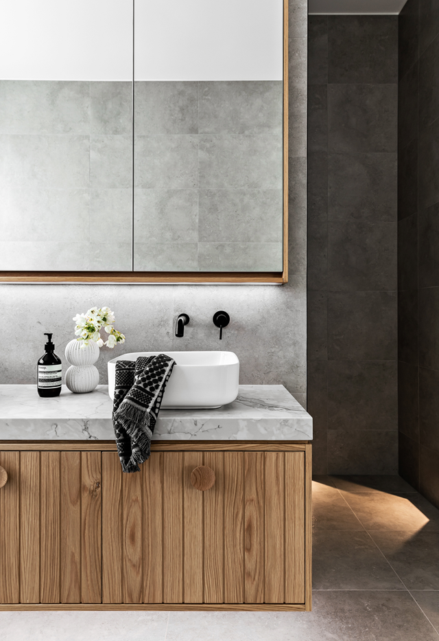 **Timber and stone**<br>
Twin basins in [this main bathroom](https://www.homestolove.com.au/contemporary-family-new-build-sydney-22465|target="_blank") are well spaced for maximum functionality. A sweeping surface on the vanity ties in nicely with large format wall and floor tiles to form a cohesive look. Black tapware ups the ante and picks up the grain in the timber joinery of the basin.