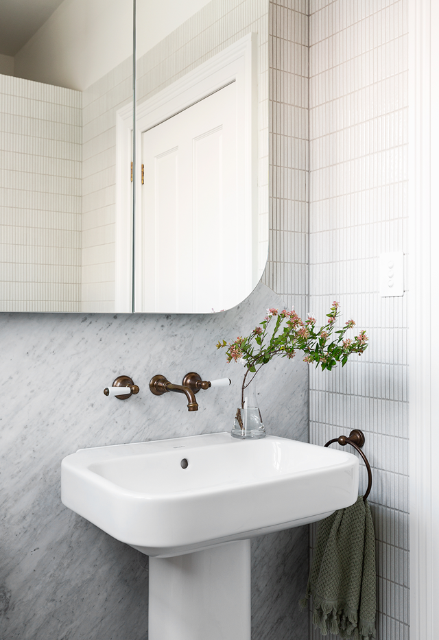 The addition of curves in a small powder room avoids sharp edges and that cramped feeling. [This renovated 19th Century home](https://www.homestolove.com.au/elegant-renovated-victorian-home-mosman-22468|target="_blank") uses modern powder room ideas to bring the space up-to-date with just the essentials - a curved, large format marble splashback, modern finger tiles and and an oversized powder room mirror to make the space appear larger.