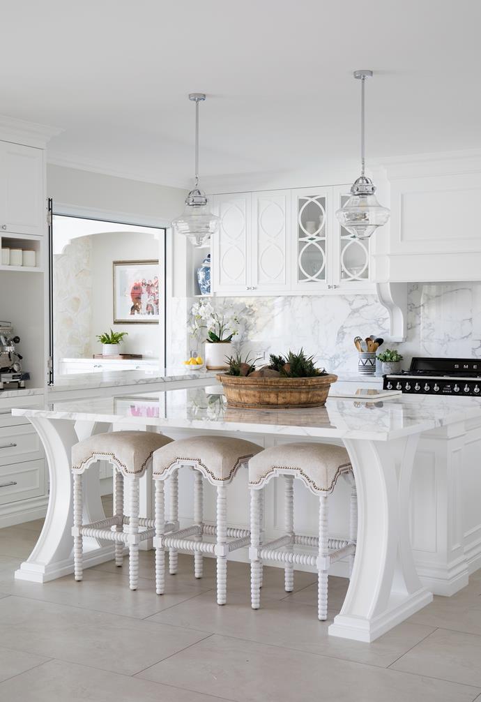 Timeless white shaker-style cabinetry is beautifully offset with luxurious slabs of Statuario marble from Finestone Granite and Marble, which runs along benches, up the splashback and spans the large 2200mm x 2200mm square island. "When the boys are home, there's six of us and we always have family and friends over on weekends, so I wanted a really deep bench we could all gather around," says Michelle, pictured with Jemma. After dark, the zone takes on another feel, with pendants from Beacon Lighting providing task lighting and LEDS within the glass cabinets creating a lovely ambient backdrop.