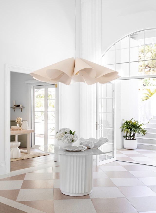An eye-catching oversized pendant light hangs above a central round table in the light and airy entryway of [this resort-style home](https://www.homestolove.com.au/resort-style-home-three-birds-renovations-22500|target="_blank").