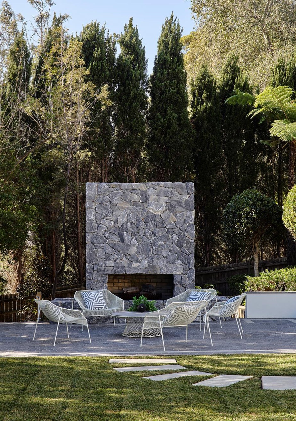 Part sculpture, part fireplace, this outdoor fireplace (designed by the inimitable [Greg Natale](https://www.homestolove.com.au/greg-natale-homes-20678|target="_blank")), proves that all you really need are the essentials to make a space work. The stone is repeated in the nearby retaining walls surrounding the swimming pool.
