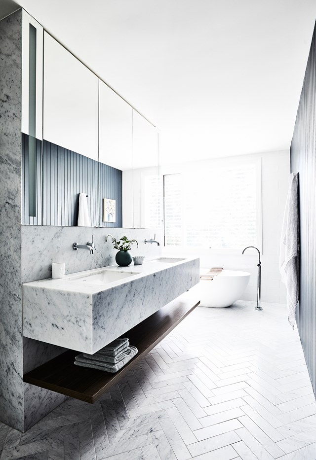 **Statement styling**<Br>
Encased in Carrara marble, the vanity in [this ensuite](https://www.homestolove.com.au/classic-bungalow-north-shore-sydney-22542|target="_blank") was custom-made and matches the herringbone floor tiles to amplify the wow factor. With a layout designed so the shower (around the corner) and bath enjoy the leafy outlook, the mirror has built-in lighting, while exterior Venetian blinds ensure privacy and northern- sun control.