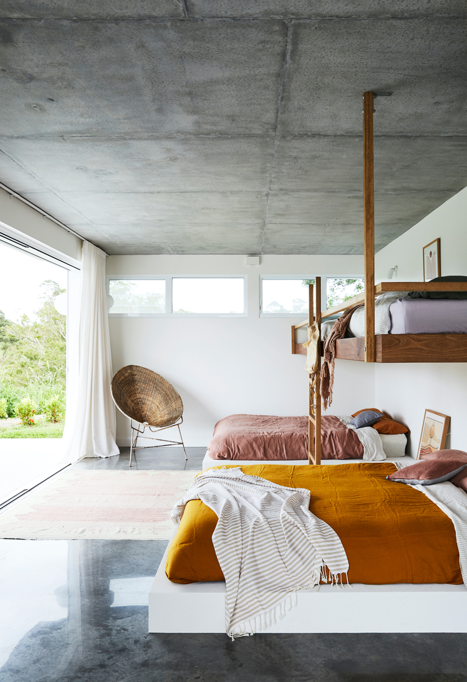 Textured linen bedding in earthy tones bring warmth to this bedroom in a sunlit [Byron Bay home](https://www.homestolove.com.au/new-build-byron-bay-hinterland-22186|target="_blank"), despite its concrete flooring and large windows.