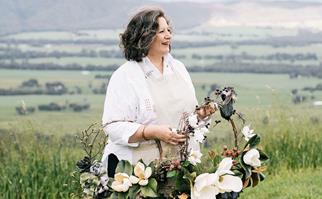 Woman holding handmade flower wreaths with green hills in the background