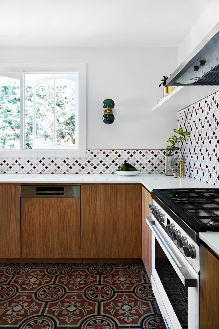 The splashback tiles in [this Moroccan-style kitchen](https://www.homestolove.com.au/lower-north-shore-sydney-home-renovation-22794|target="_blank"), speak to the homeowner's love of travel. Smooth benchtops allow the tiles to do the talking, while floor tiles and an emerald wall sconce layer more colour.