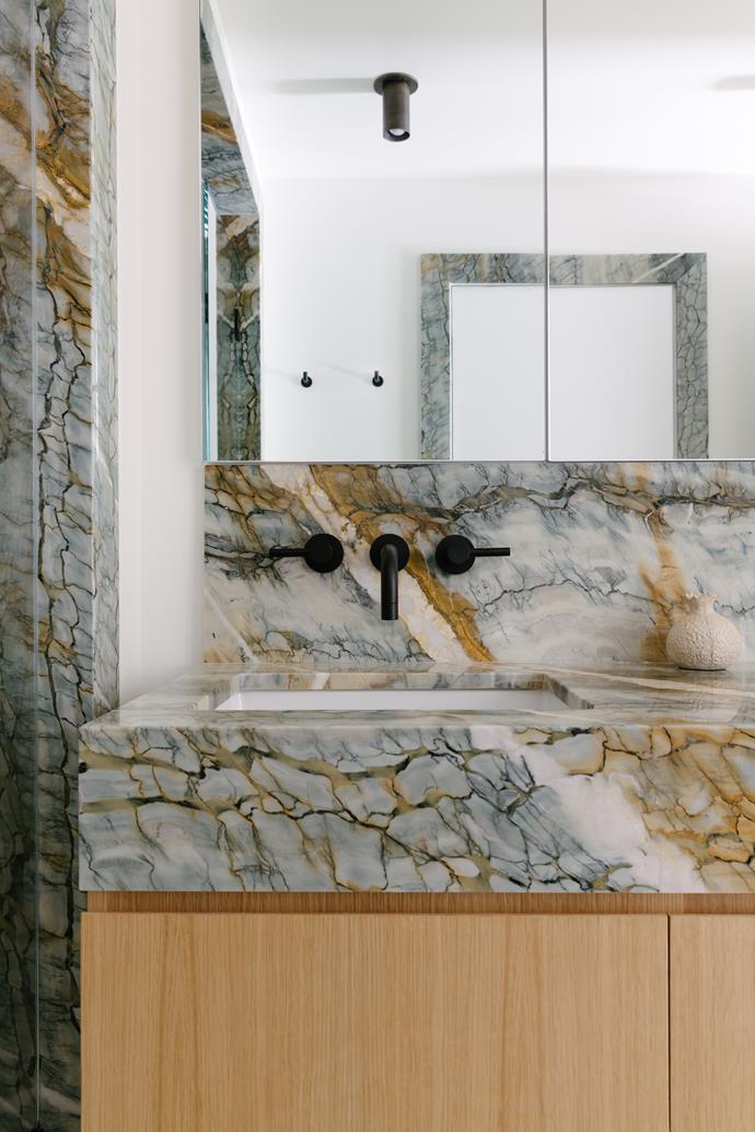 The master bathroom features custom white oak cabinetry, marble from BAS Stone NYC and Newport Brass tapware. The ceiling spotlight is from Made.