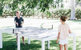 Two kids playing table tennis outdoors