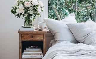 Bedroom with a vintage timber bedside table topped with freshly arranged flowers