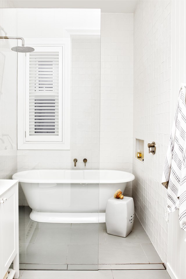 Maximising use of available space, a Victoria & Albert tub is tucked behind the shower in [this renovated Federation family home](https://www.homestolove.com.au/bright-federation-renovation-22943|target="_blank"). All white surfaces keep things light and bright, while plantation shutters, a vintage ceramic stool and a recessed wall niche offer modern convenience.