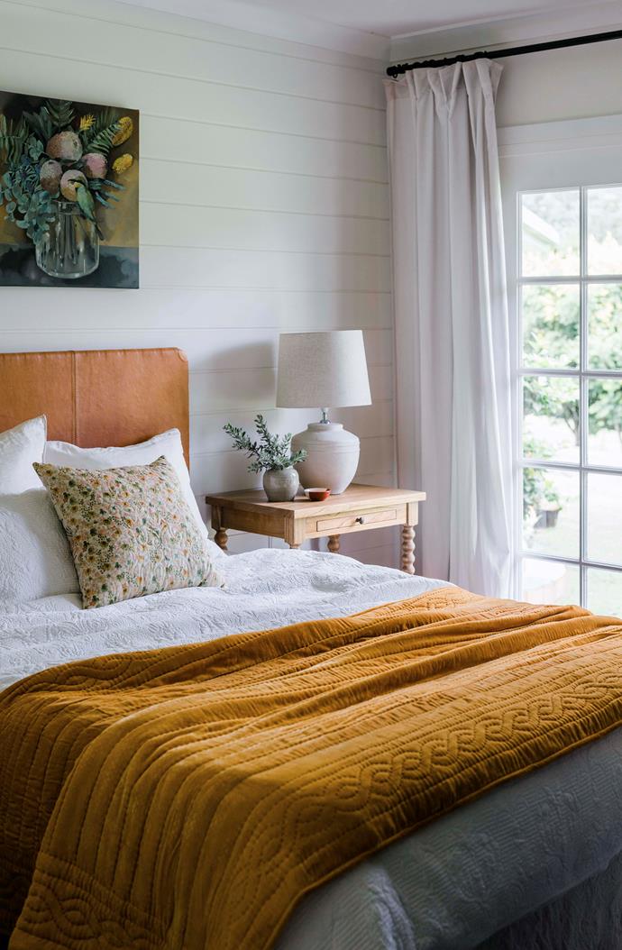 An abundance of warmth fills this [farmhouse bedroom](https://www.homestolove.com.au/90s-brick-farmhouse-renovation-22951|target="_blank"), which features hues of earthy oranges and both natural and soft lighting.