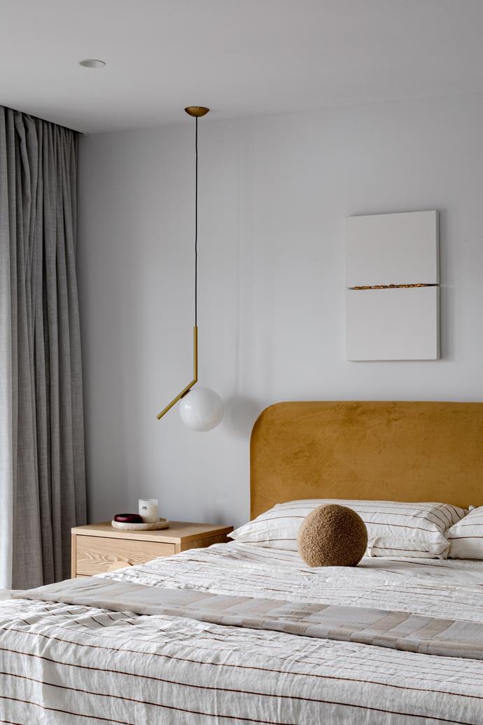 Stripes and long lines give the master bedroom a unique, streamlined feel. The bedhead is Heatherly Design, the bedlinen is Cultiver, the blanket is by Curio and the brass light is by Flos.