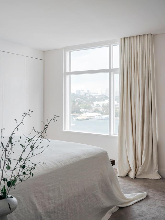 Linen furnishings and soft grey carpet set a meditative tone in the water-facing bedroom in this [harbourside apartment](https://www.homestolove.com.au/harbourside-apartment-with-minimalist-interior-21376|target="_blank") with a warm, minimalist interior by Tania Handelsmann and Gillian Khaw of Handelsmann + Khaw.