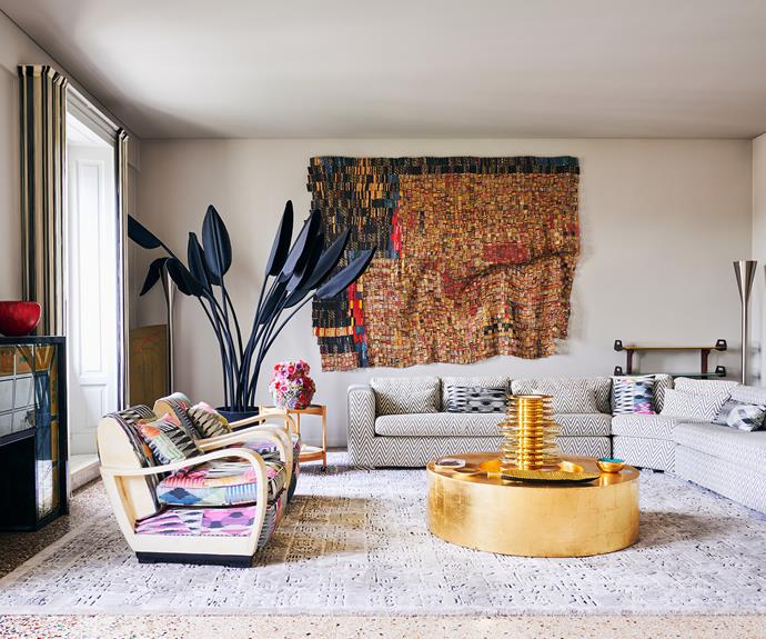 Rosita's aesthetic translates to her [homewares](https://www.homestolove.com.au/best-online-furniture-and-homewares-stores-21001|target="_blank") and textile designs, which are on show in this living space. The rug, zig-zag sofa upholstery and the fabric on the [vintage armchairs](https://www.homestolove.com.au/decorating-with-vintage-furniture-21043|target="_blank") is Missoni Home. The golden [coffee table](https://www.homestolove.com.au/10-of-the-best-coffee-tables-13248|target="_blank") is by the Salvatore + Marie atelier in Milan. A mirrored [Art Deco](https://www.homestolove.com.au/art-deco-house-19892|target="_blank") drinks cabinet behind the armchairs creates the visual illusion of a real fireplace, and was originally from a cruise ship. The piece that ties this room together is the exquisite tapestry by artist El Anatsui. Rosita says she fell in love with this wall hanging at Rossana Orlandi Gallery and immediately purchased it.