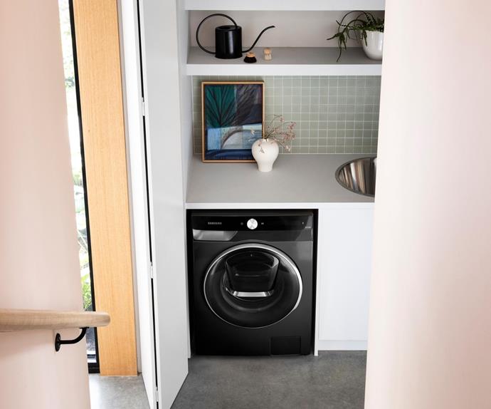 Black smart washing machine in a contemporary laundry with polished concrete floor and white benchtop