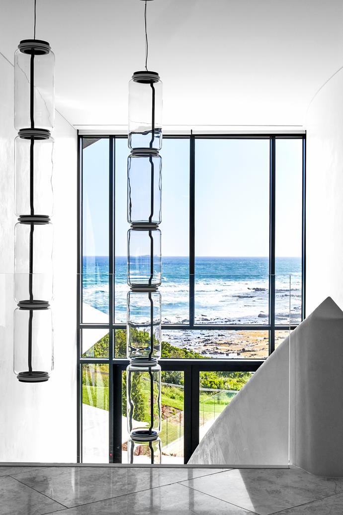 'Noctambule' blown-crystal pendant lights from Euroluce drape in the void without impeding the view. St Croix natural stone flooring from CDK Stone.