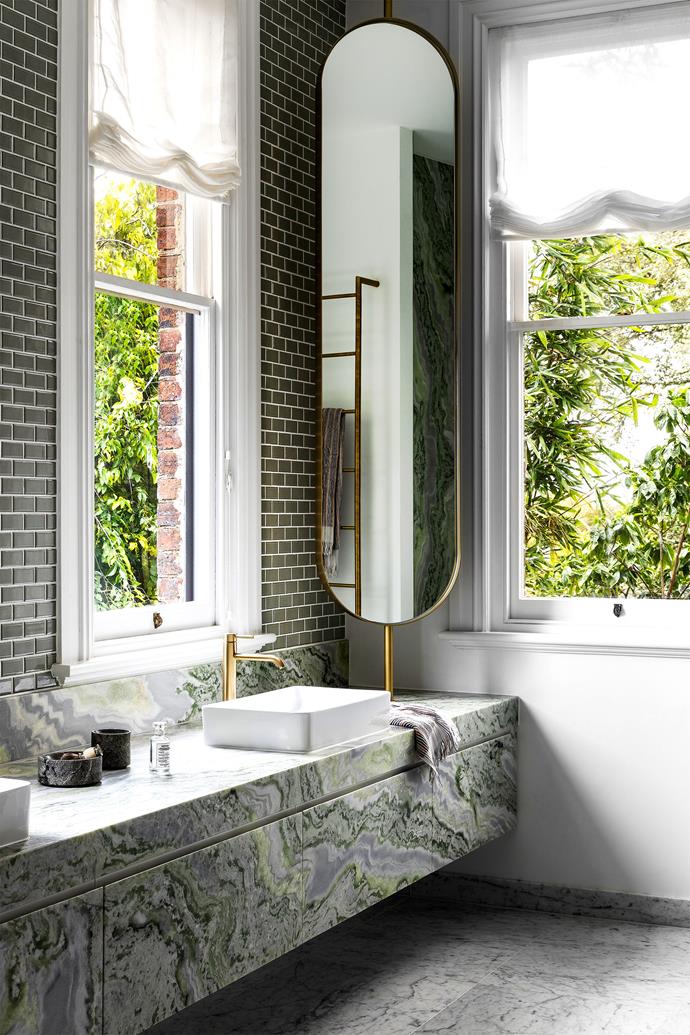 In what was formerly a [formerly dilapidated 19th-century mansion](https://www.homestolove.com.au/historic-mansion-renovation-23164|target="_blank"), this breathtaking master ensuite bathroom features a vanity clad in green quartzite from Signorino alongside a custom mirror, green bevilled wall tiles and Bianco Carrara flooring. The master, originally located elsewhere, benefits from views out to the surrounding trees. "There's an incredible calmness about being surrounded by nature up here," says the owner. "It's a view and feeling that we thought deserving of this space."