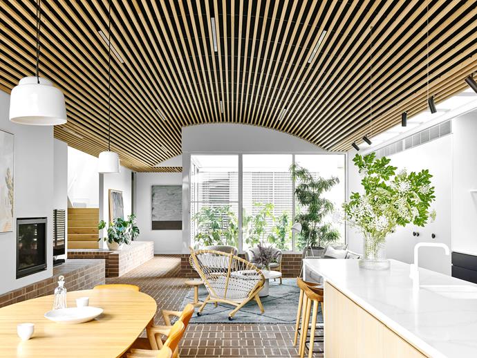 A small courtyard behind the living room brings natural light deep into the house. The circle chair is from Great Dane, and the De Sede DS612 coffee table is from Domo. The pendant lights hanging over the dining table are from Design Nation.