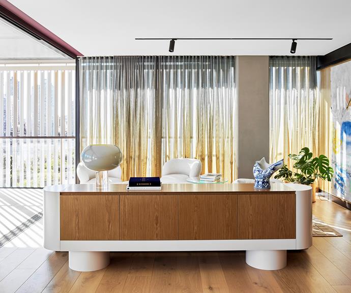 [Basele Shopfitting](https://www.basele.build/|target="_blank"|rel="nofollow") built the custom joinery, including this timber veneer sideboard, which acts as a visual boundary between the living and kitchen/dining spaces. "Raising the joinery off the floor makes the spaces feel generous and delicate," says Joel, who adds that the extra height allows easier access to the contents for the owners. The rounded edges are a safety feature while bringing a sense of flow and continuation to the overall design. A Foscarini 'Buds 2' table lamp and Moooi 'Blow Away' vase from [Space](https://www.spacefurniture.com.au/|target="_blank"|rel="nofollow") sit on top.