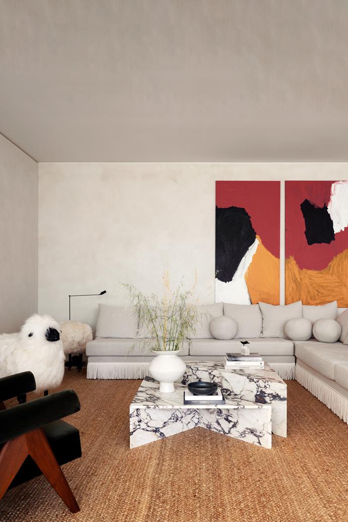 Texture and a muted palette rule in the living room with a shot of bold colour inserted via a pair of Sally Gabori artworks. Custom sofa and coffee table in [Calacatta Viola marble](https://www.homestolove.com.au/viola-marble-trend-23175|target="_blank"). Pierre Jeanneret re-edition armchair from Tigmi Trading. Jute rug from International Floorcoverings. Lumina 'Daphine' floor lamp by Tommaso Cimini from Enlightened Living. The Claude Lalanne-inspired sheep was found online.