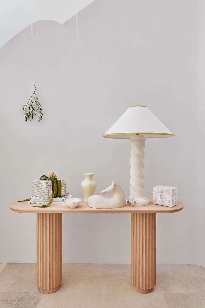 A timber console table decorated with a [beautifully wrapped present](https://www.homestolove.com.au/7-tips-for-wrapping-christmas-gifts-6027|target="_blank"|rel="nofollow") and fresh foliage.