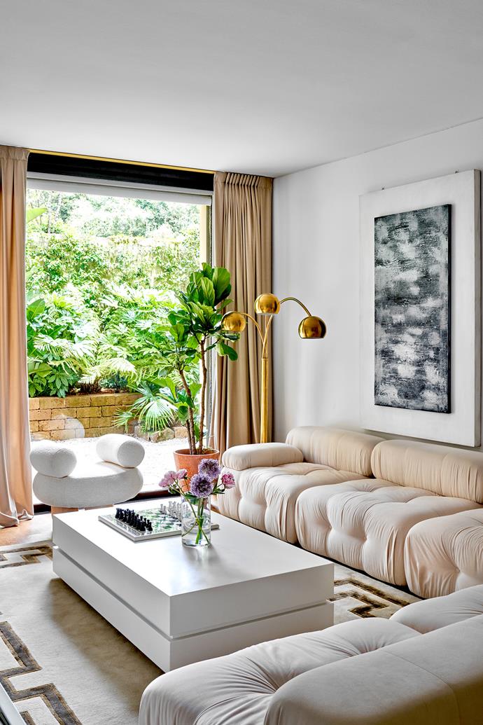 A glass sliding door separates the garden from the living room, which features a sofa custom-made by local craftsmen. The curvy Bling Bling armchair is by Pietro Franceschini, the 1970s Formica laminate coffee table is by Roberto Monsani for Acerbis, the artwork is by Alberto Rapetti and the rug is Studio Maleki.