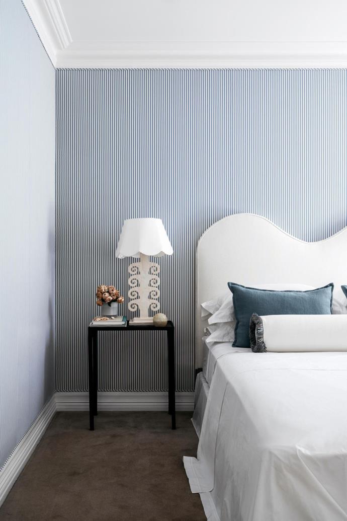 This custom boucle bed head feels balanced against a blue striped wallpaper, while still creating a a sense of intrigue with a unique curved form at [this classic Sydney home](https://www.homestolove.com.au/a-classic-sydney-home-decorated-with-contemporary-and-antique-pieces-20209|target="_blank") decorated with both contemporary and antique pieces. 