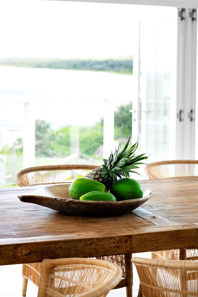 In the dining room, a bowl from Amara Home adorns a timber table, where guests are treated to delicious food and the best view in the house.