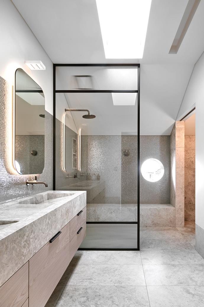 In the master ensuite, 'Neutra 6.0' glass wall tiles in B Ferro from Di Lorenzo. Floor tiles and vanity top in honed 'Grigio Imperiale' limestone from Granite & Marble Works. Metal recessed pull handles from MadeMeasure. LED strip lighting from Tovo Lighting.