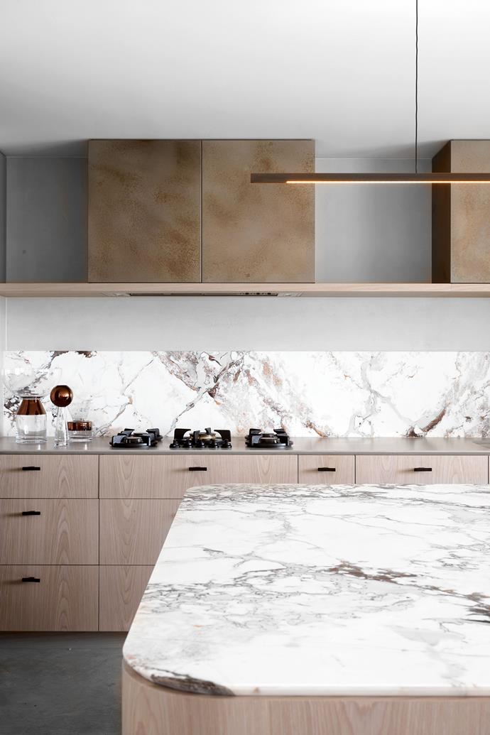 Kitchen benchtop and splashback in Brescia Capria Royal marble from Worldstone. Rangehood and overhead cupboard in Nickel Smooth Texture in 'Pearl Patina' from Axolotl. Joinery in re-toned fumed oak from George Fethers. Rakumba 'Highline' pendant light from Design Nation.