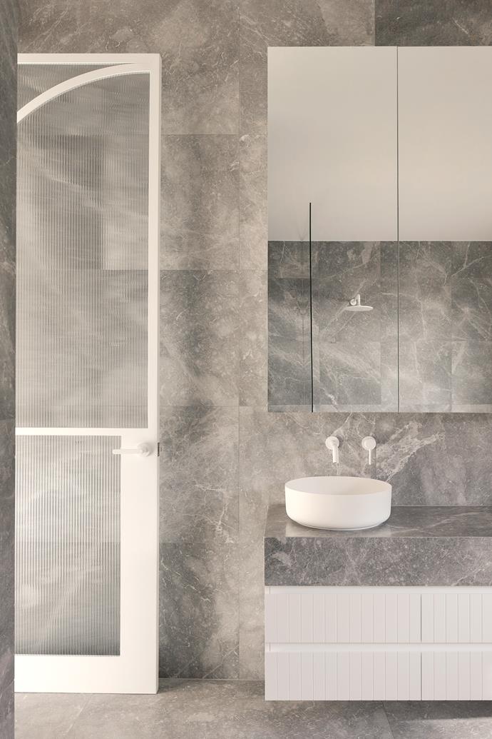The same luxurious Hermes stone from the kitchen appears en masse in the bathrooms for a touch of decadence and drama. The top-mounted vanity and matte white tapware from [ABI Interiors](https://www.abiinteriors.com.au/|target="_blank"|rel="nofollow") add a pop of freshness.