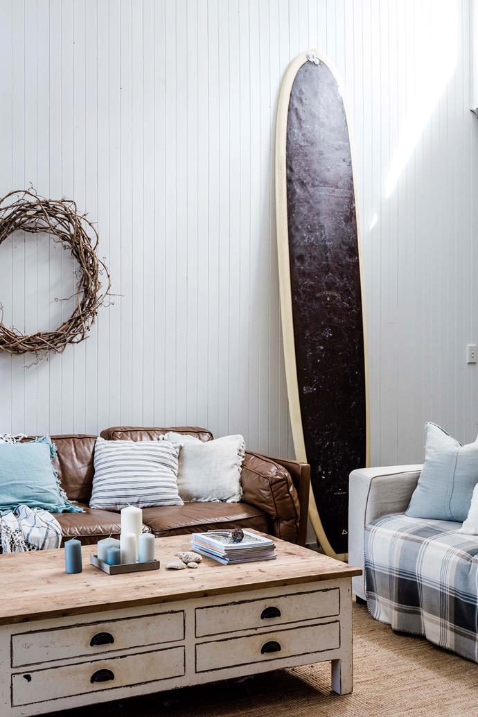 A vintage McTavish surfboard on show in the loungeroom. "It's awesome - we put the kids on the front and surf with them," Katie says. [The Eclectic Style](https://www.eclecticstyle.com.au/|target="_blank"|rel="nofollow") coffee table and linen sofa sit alongside a leather sofa from Freedom. 