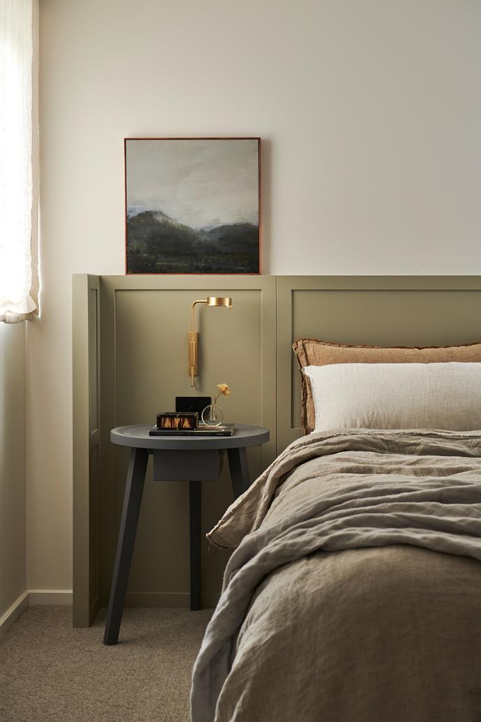Custom joinery in a calming olive hue sets the scene for the monotonal main bedroom of this [renovated Surf Coast home](https://www.homestolove.com.au/minimal-coastal-renovation-surf-coast-23312|target="_blank"). A soft artwork by Greg Wood sits atop the bedside, complementing the textures and tones of the Hale Mercantile bedding.