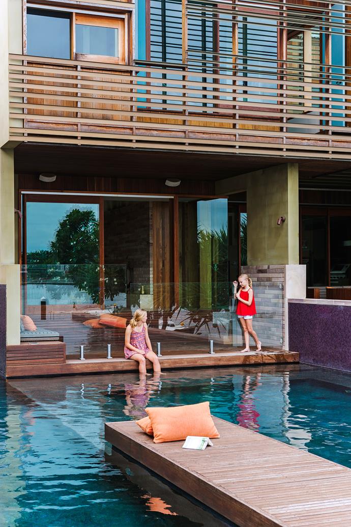 Timber decking not only surrounds the pool of [this Eastern aesthetic-inspired new build](https://www.homestolove.com.au/eastern-aesthetic-inspires-new-build-in-brisbane-3805|target="_blank") in Brisbane, but continues up the wall, and has been fashioned into a built-in bench seat that looks like it's floating on the water. 