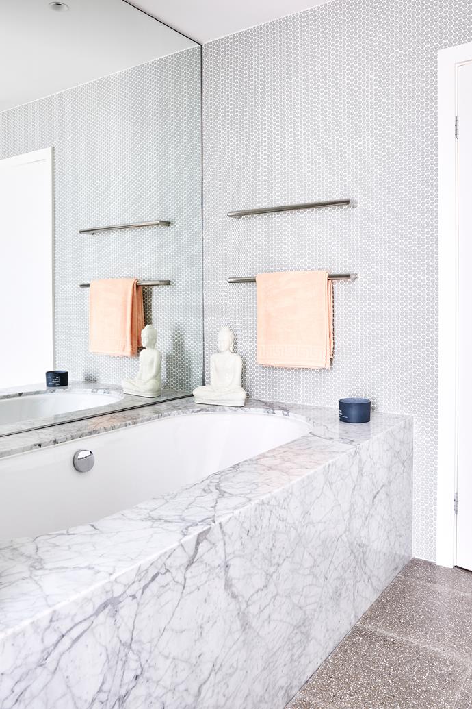 **BATHROOM** A generous inset bathtub is draped in elegant Carrara marble, while penny rounds take marble up to ceiling height.
