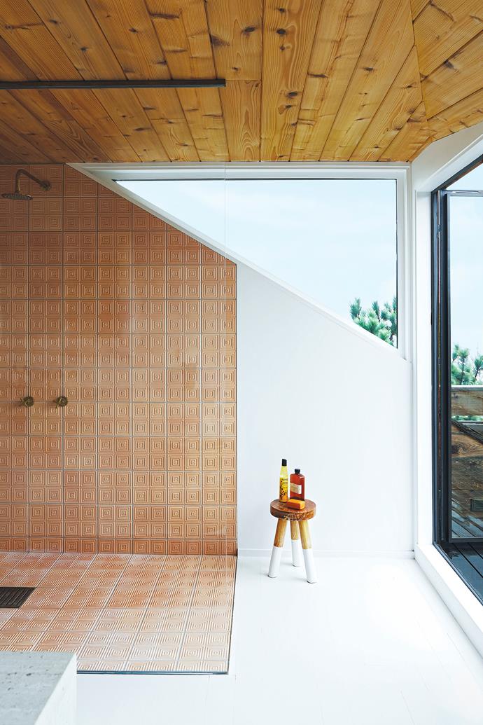 To expand this wet area, the layout and roofline were reconfigured by architect Clay Coffey. The triangular window is offset by the clean lines of the shower featuring terracotta tiles by Villa Lagoon while a door leads to a balcony overlooking the dunes.