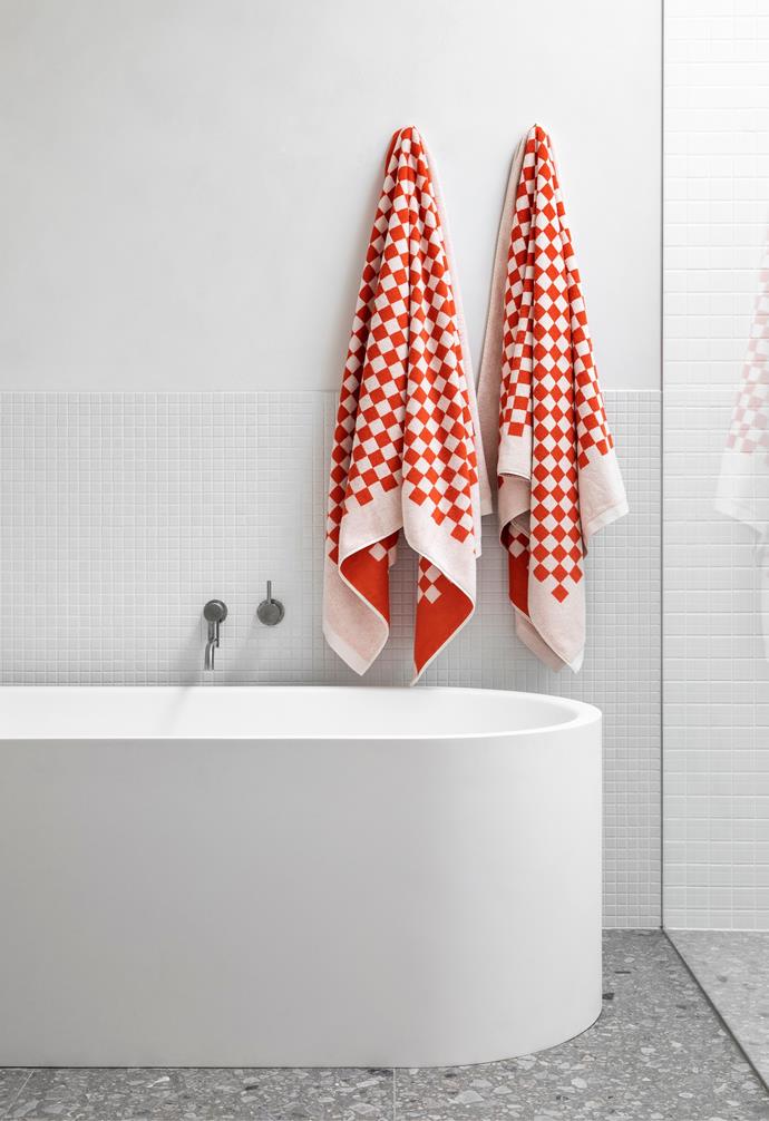 Two [Baina towels](https://shopbaina.com/collections/all|target="_blank"|rel="nofollow") in paloma sun and ecru hang over the bath in this flawless family home that utilises robust materials, playful shapes and calm colours.