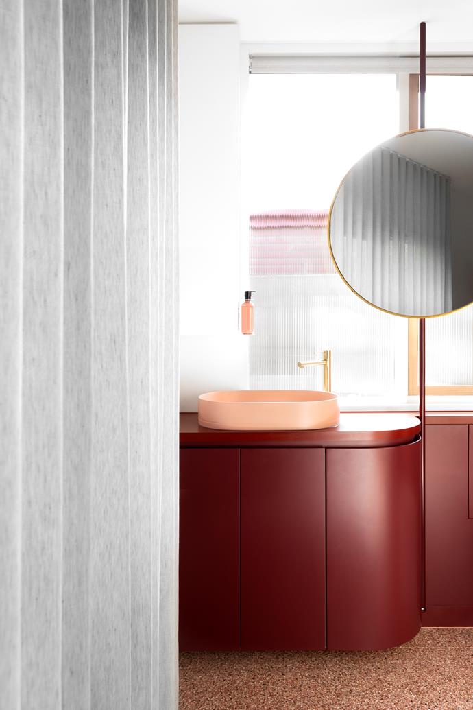 Curves create a sense of softness, from the custom vanity in Dulux 'Red Wine' to the pink basin by Nood. A brass tap from Phoenix Tapware matches the mirror frame, injecting some glamour, while coloured terrazzo tiles from Signorino add some fun.