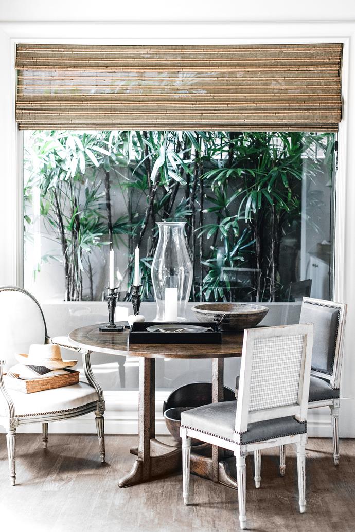 At one end of the kitchen is a French fruitwood table with painted Louis XV chairs overlooking a lush planting of palms in the garden outside.