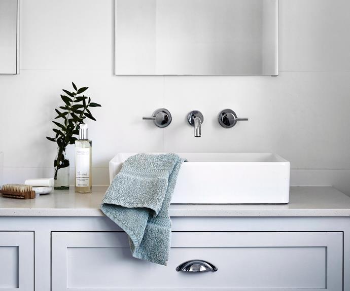 Blue hand towel in a white sink atop a blue, shaker style bathroom vanity