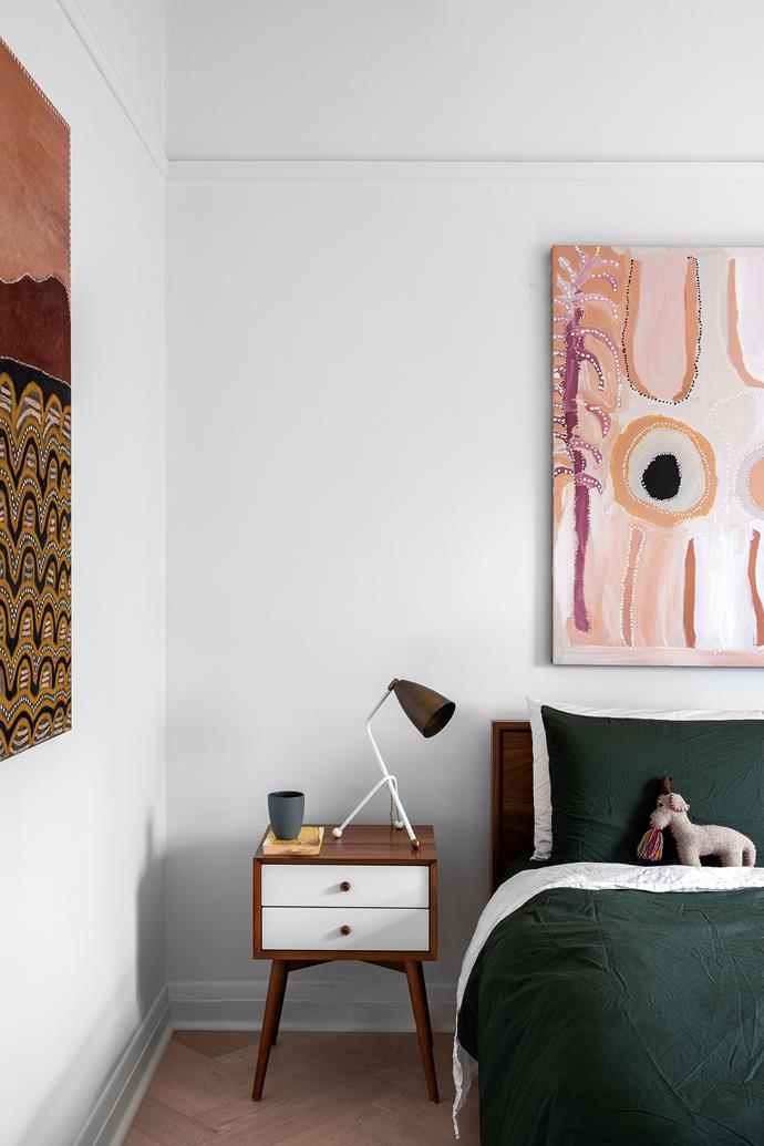 In the main bedroom, the bedside drawers and lamp were bought in San Francisco. The painting on left is a dyptique by Nancy Nodea, and the painting above the bed is by Tjukupati James.