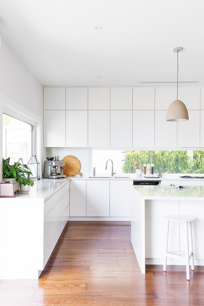 A glass splashback in this kitchen adds lush green to an otherwise neutral colour palette and makes the most of the garden view.