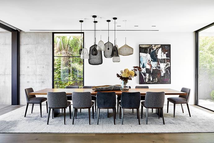 The owners are keen entertainers and this generous table (Riva 'Sky Natura' dining table from Fanuli), extending the full length of the dining area from one outdoor area to another, is designed for a crowd. Mix of 'Kute' pendant lights from Spence & Lyda. Antonia Mrljak artwork on wall from Becker Minty.