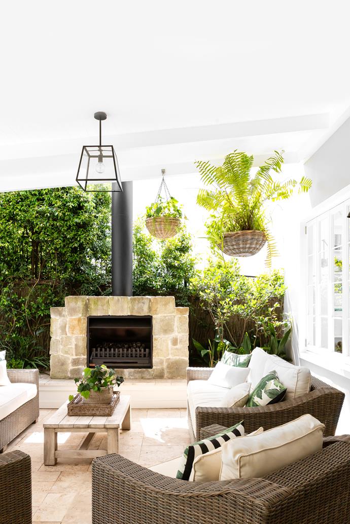 The outdoor space of this once [dilapitated 1970s house](https://www.homestolove.com.au/refined-georgian-meets-hamptons-style-home-23417|target="_blank") features a gorgeous built-in stone fireplace. Capturing the essence of outdoor living in Australia, there's nothing about this zone that screams exclusivity to one season – cosy sofas and the hardy fireplace meet a light, bright outlook with plenty of greenery.