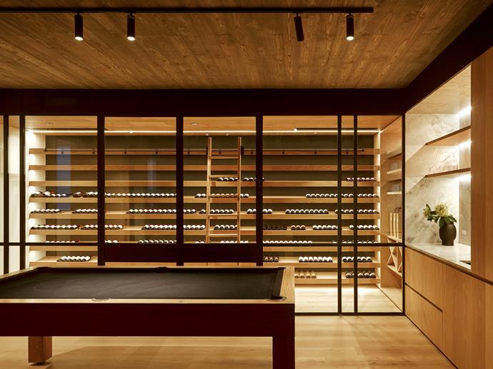 Illuminated by light flooding in via the glass-sided swimming pool, the games room looks through to the [well-stocked wine cellar](https://www.homestolove.com.au/wine-storage-ideas-19876|target="_blank") with oak veneer cabinetry by Minka Joinery.