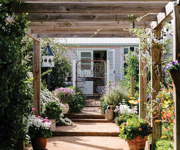 Beyond the arbour is the summer house, which is painted in Dulux Petite Pink. The stained-glass windows came from a local church, while the French doors and ornate iron gate were bought at farms not far from home. The potager sits in the back right-hand corner of the garden.