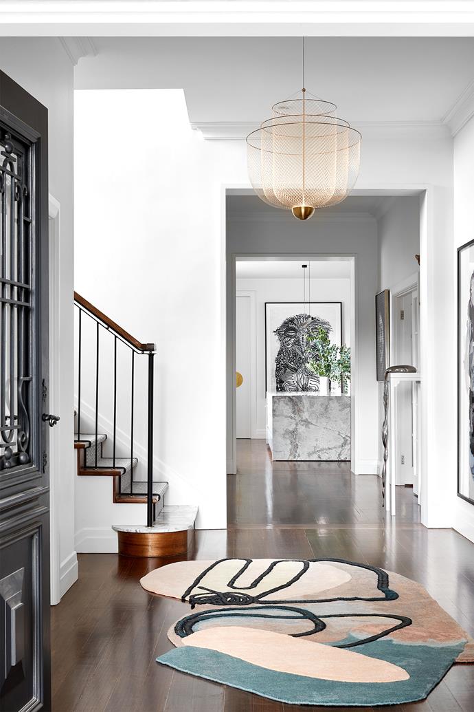 In the entry the staircase, in timber with custom steel, brass and timber handrail by Lucy Clemenger Architects, was repositioned. A [cc-tapis rug](https://www.1stdibs.com/creators/cc-tapis/furniture/rugs-carpets/|target="_blank"|rel="nofollow") from Loom, Mountain and Streams sculpture on stand by Lee Chin-fai Danny and AK-47 artwork by Zhang Dali. Looking into the kitchen with Sooty Owl by Joshua Yeldham.