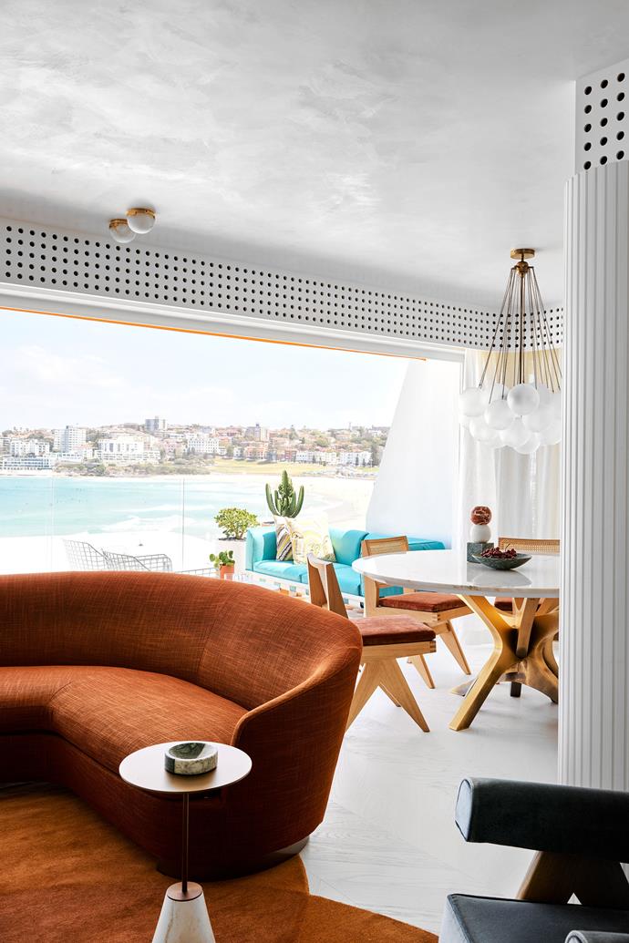 A custom Greg Natale 'Eclipse' rug from Designer Rugs anchors the sitting area with a Minotti 'Jacques' angled sofa from De De Ce in [this re-energised Bondi Beach apartment](https://www.homestolove.com.au/playful-bondi-beach-apartment-23382|target="_blank") by Greg Natale. While teal is a continuing tone throughout the home, the pops of orange in the living room extend to the outdoor balcony with custom tiles designed by Greg.