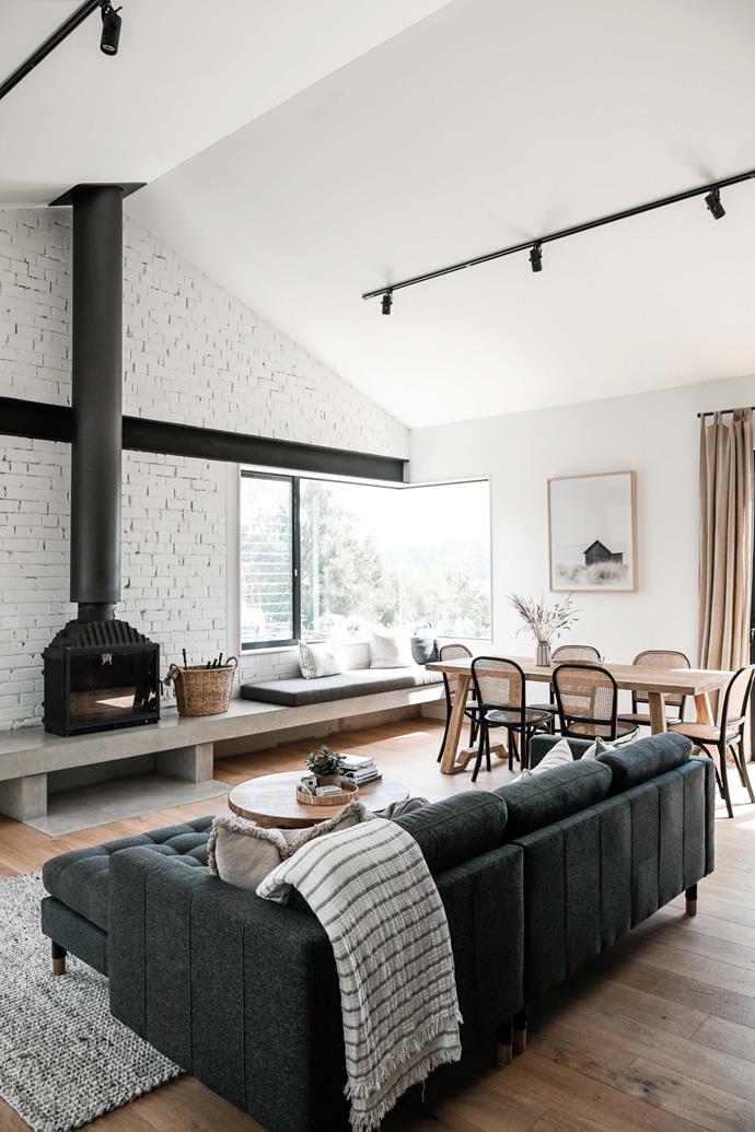 A raked ceiling and wrap-around windows make the most of natural light and picturesque views in the living room of [The Barn at Rangeview](https://www.homestolove.com.au/the-barn-at-rangeview-country-accommodation-23464|target="_blank"), a modern barn-style accommodation. The Cheminee fireplace at the back of the space is, according to owner Wanita, the star of the space, inviting guests to gather with a glass of wine and a good book.