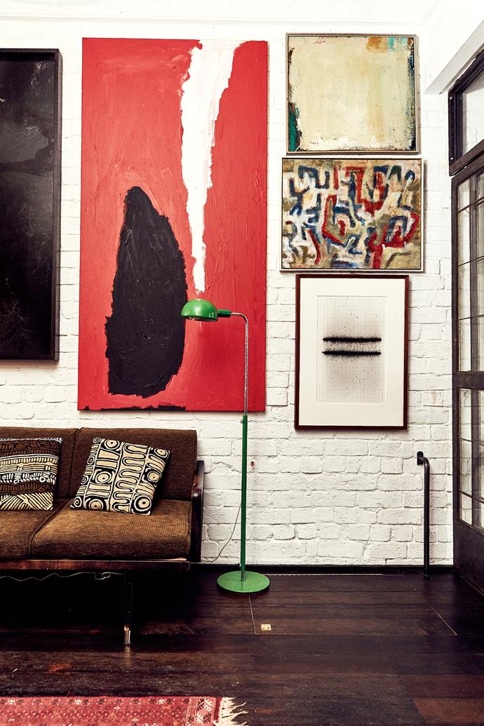 Original brick walls painted Dulux Lexicon Quarter form a textural backdrop for Lottie and James' art collection. The sofa was sourced on Gumtree and reupholstered. The floor lamp was a gift. Artworks (from left) by Sarah Mosca, Sally Gabori, Ross Mullane, Tony Mighell and Ben Gallagher.